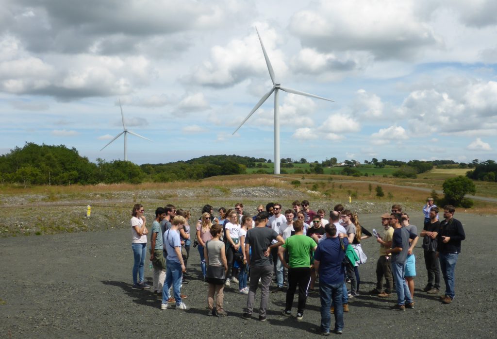 The Students at on the Hardstanding of Turbine 1 of GreenPower's Drumduff Wind Farm with Turbines 2 and 3 in the Background